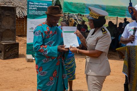 man is given his land use agreement by a woman in uniform.